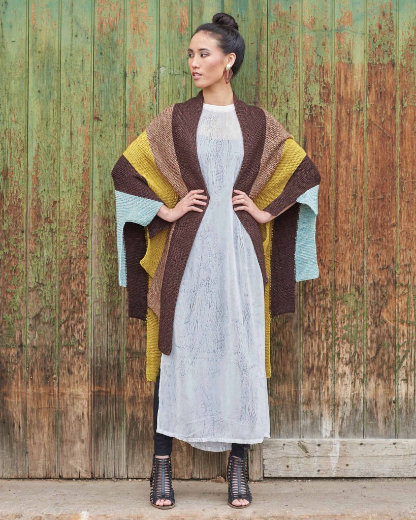 Color-blocked wrap from Urban Knit Collection, worn against a weathered green wooden door
